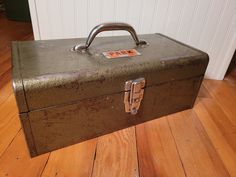 an old metal box sitting on top of a hard wood floor next to a wall