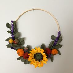 a sunflower and other flowers are arranged on a circular wall decoration with leaves, oranges, and lavenders