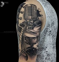 a man's arm with a microphone and musical instruments tattoo on the left shoulder