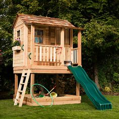 a wooden play house with a green slide