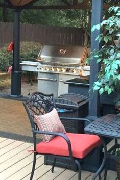 an outdoor grill and table with chairs around it