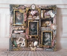 an altered photo frame with cats and other items on it's sides, sitting in front of a wall