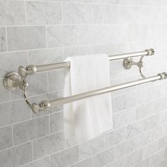 two towel racks in a bathroom with white marble tiles on the walls and flooring