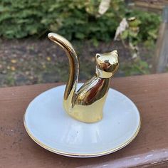 a gold cat figurine sitting on top of a white plate