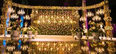 an outdoor wedding setup with chandeliers and flowers on the side, reflecting in water