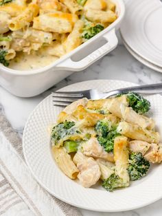 a white plate topped with pasta covered in chicken and broccoli next to a casserole dish