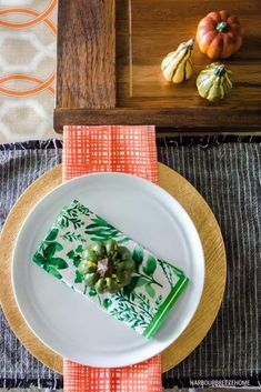 a white plate topped with a piece of cake next to an orange and green napkin