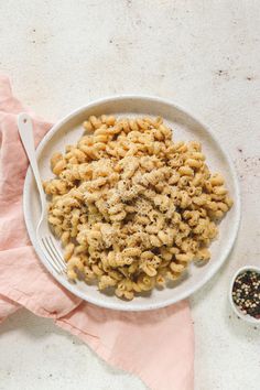 a white bowl filled with macaroni and cheese on top of a pink napkin