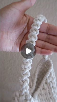 someone is holding a white crochet bag in their hand and it looks like they are making something out of yarn