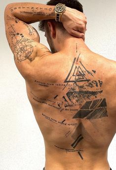 a man with tattoos on his back is holding his hand to his head and looking at the camera