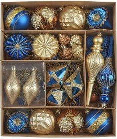 an open box filled with assorted christmas ornaments and decorations in blue and gold colors