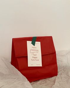 a red paper bag with a green ribbon on it and a tag hanging from the top