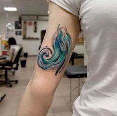 this watercolor wave tattoo on the left arm is really cool and it's blue