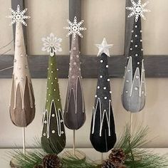 a group of christmas trees sitting on top of a table next to pine cones and decorations