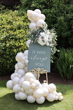 a sign that says it was always you surrounded by white balloons and greenery in the background