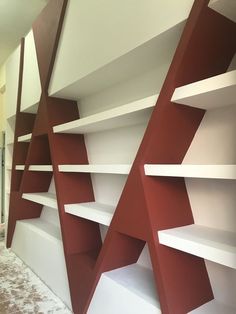 an empty room with red and white shelving on the wall next to a carpeted floor