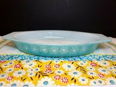 a blue bowl sitting on top of a yellow and white place mat next to a plate