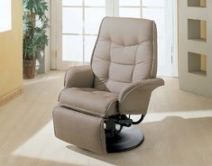 a reclining chair in a living room with white walls and wood flooring, along with a potted plant