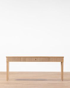 a wooden table sitting on top of a hard wood floor next to a white wall