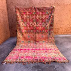 an old rug is laying on the floor in front of a wall with concrete floors