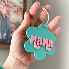 a person holding up a keychain with the word mama on it