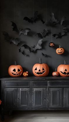 halloween pumpkins are sitting on top of an old dresser in front of a black wall