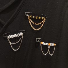 three pieces of metal with chains attached to them, one has an orange bead on it