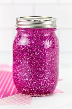 a purple glitter jar sitting on top of a pink table