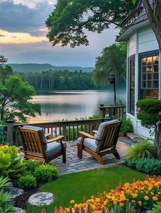 two wooden chairs sitting on top of a lush green field next to a body of water