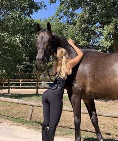 a woman standing next to a brown horse