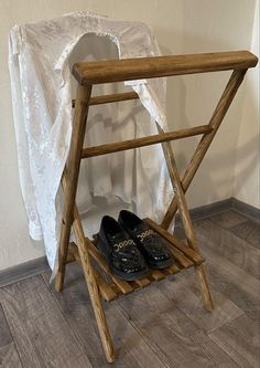 a pair of black shoes are on a wooden shoe rack in front of a white curtain