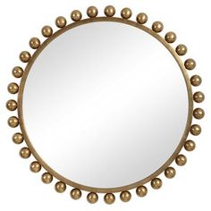 a round mirror with gold balls on the rim and an oval mirror frame in the middle