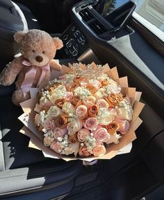 a teddy bear sitting in the back seat of a car next to a bouquet of flowers