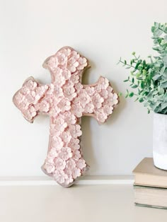 a wooden cross sitting on top of a table next to a potted plant