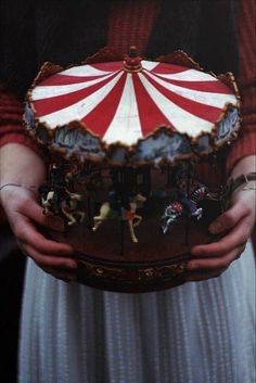 a person holding a miniature carousel in their hands