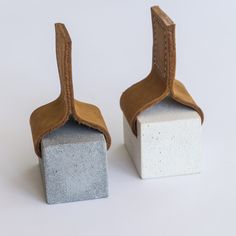 two cement blocks with leather straps on them, one is white and the other is brown