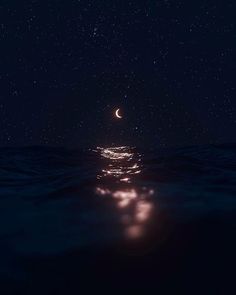 the moon is shining in the night sky over the ocean with water and stars above it