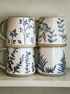 three blue and white mugs sitting on top of a shelf