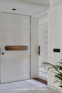 a white door with a wooden handle on the side and a plant next to it