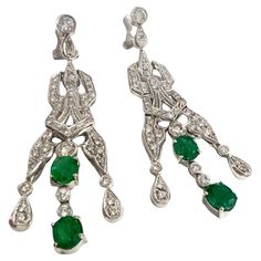 These earrings showcase an Art Deco design, crafted in platinum 950 and adorned with brilliant-cut Diamonds and an oval-cut Emerald. The Diamonds total 2.24 carats and are of SI clarity and H-I color grade. The Emerald is 2.47 carats and is oval-cut. The earrings have a weight of 18.94 grams and feature a unique 250.8 setting. They measure 5.8 cm in length. **IN STOCK** Characteristics: Material: Platinum 950 Diamonds: 2.24 ct total, Brilliant Cut, SI Clarity, H-I Color Emerald: 2.47 ct, Oval Cu Art Deco Drop Earrings, Platinum Earrings, Style Art Deco, Emerald Bead, Colombian Emeralds, Estilo Art Deco, Art Deco Earrings, Emerald Stone, Beaded Dangle Earrings