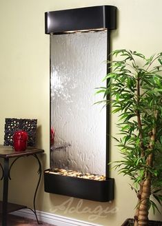 a wall mounted fountain in the corner of a room with a potted plant next to it