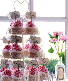 cupcakes with pink frosting are arranged in the shape of a tree on a table