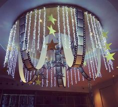 a chandelier with stars hanging from it's sides and lights on the ceiling