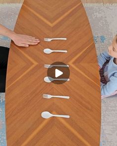 a young child sitting at a table with spoons and forks on top of it