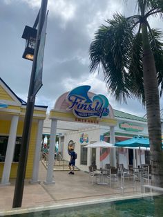 a person standing in front of a building with a pool and palm trees around it