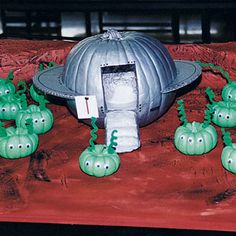 some green plants are growing in front of a silver object on a red table cloth