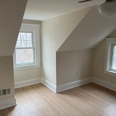 an empty room with hard wood floors and two windows