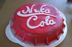 a red cake with white frosting that says nuka cola on it, sitting on top of a table