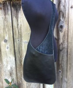 a black leather purse hanging on a wooden fence