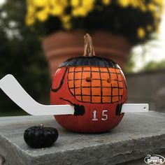 a pumpkin with a hockey stick sticking out of it's side sitting on a ledge